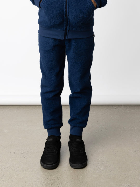 Minti kids clothing. Super cosy and soft loose leg trackies made in teddy with 2x2 rib cuffs. Front pocket to keep hands warm. Small Minti embroidery on the back. 70% Polyester // 30% Cotton.