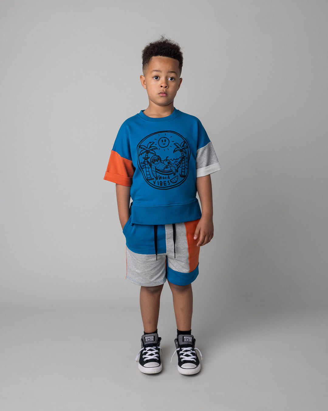 Kid wearing the Sliced Short in teal and orange and grey marle with the Chill Sloth Short Sleeve Crew in teal and orange and grey marle, front view