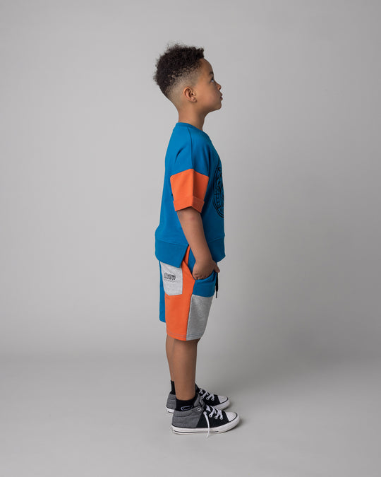 Kid wearing the Sliced Short in teal and orange and grey marle with the Chill Sloth Short Sleeve Crew in teal and orange and grey marle, side view