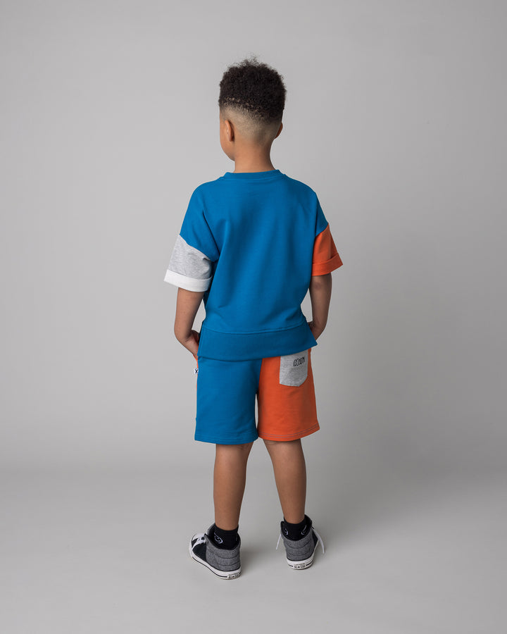 Kid wearing the Sliced Short in teal and orange and grey marle with the Chill Sloth Short Sleeve Crew in teal and orange and grey marle, back view