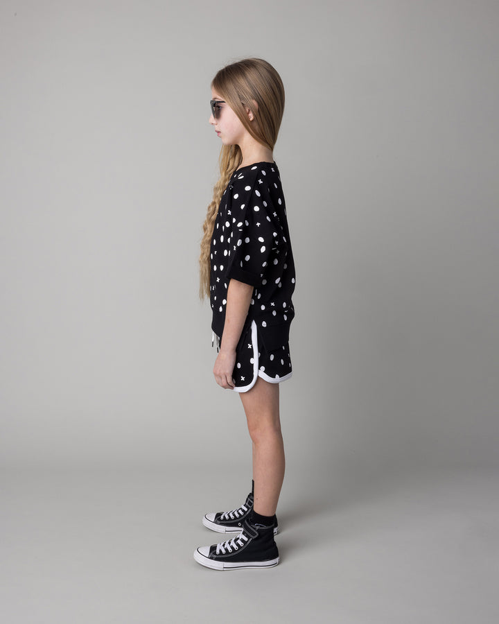 Kid wearing the Spotty Short Sleeve Crew in black with the Spotty Short in black and white, side view