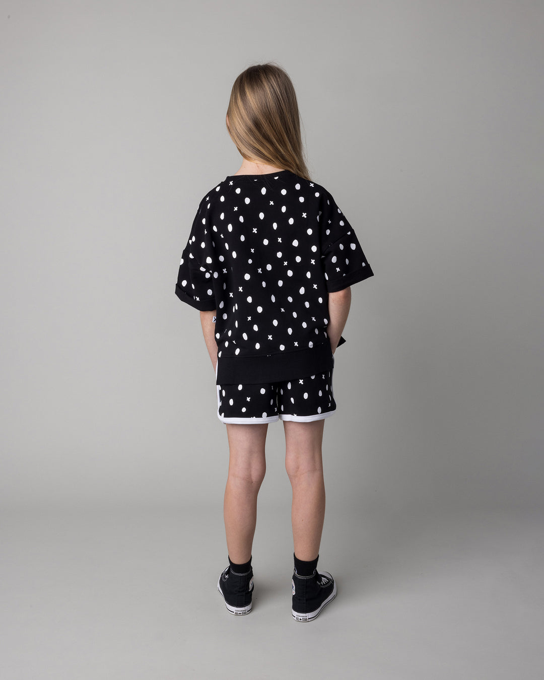 Kid wearing the Spotty Short Sleeve Crew in black with the Spotty Short in black and white, back view