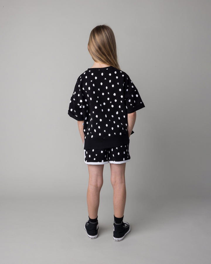 Kid wearing the Spotty Short Sleeve Crew in black with the Spotty Short in black and white, back view