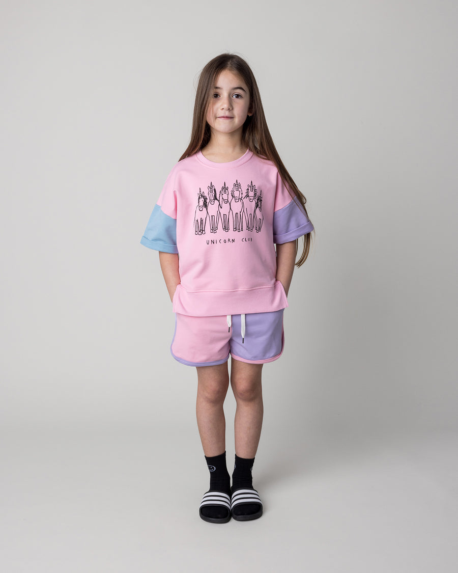 Kid wearing the Unicorn Club Short Sleeve Crew in pink, purple and aqua with the Sprint Short in pink, purple and aqua, front view