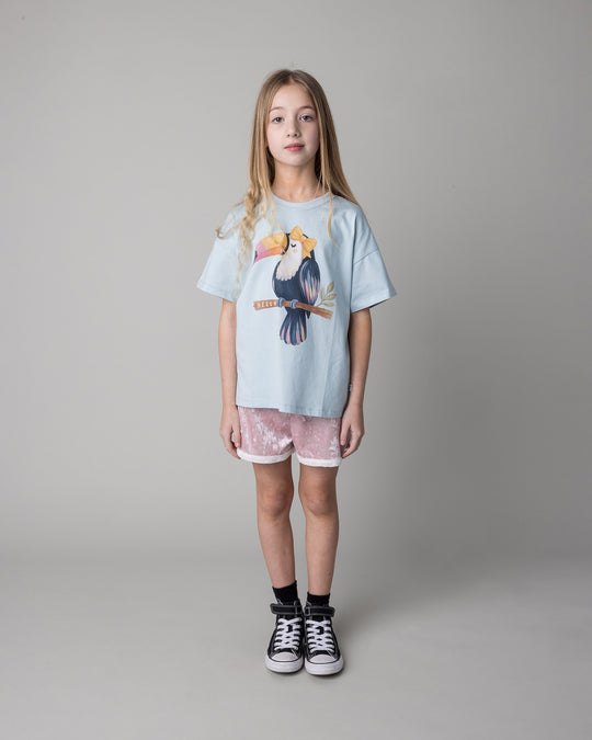 Kid wearing the Hello Toucan Tee in light blue with the Velvet Runner Short in blush and cream, front view