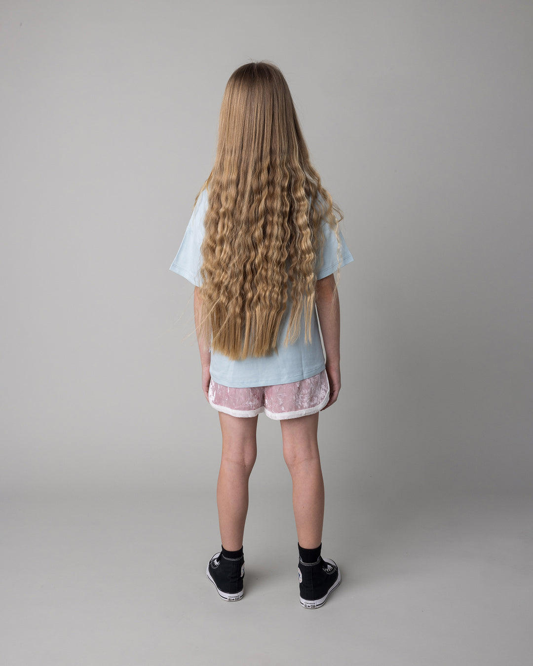 Kid wearing the Hello Toucan Tee in light blue with the Velvet Runner Short in blush and cream, back view