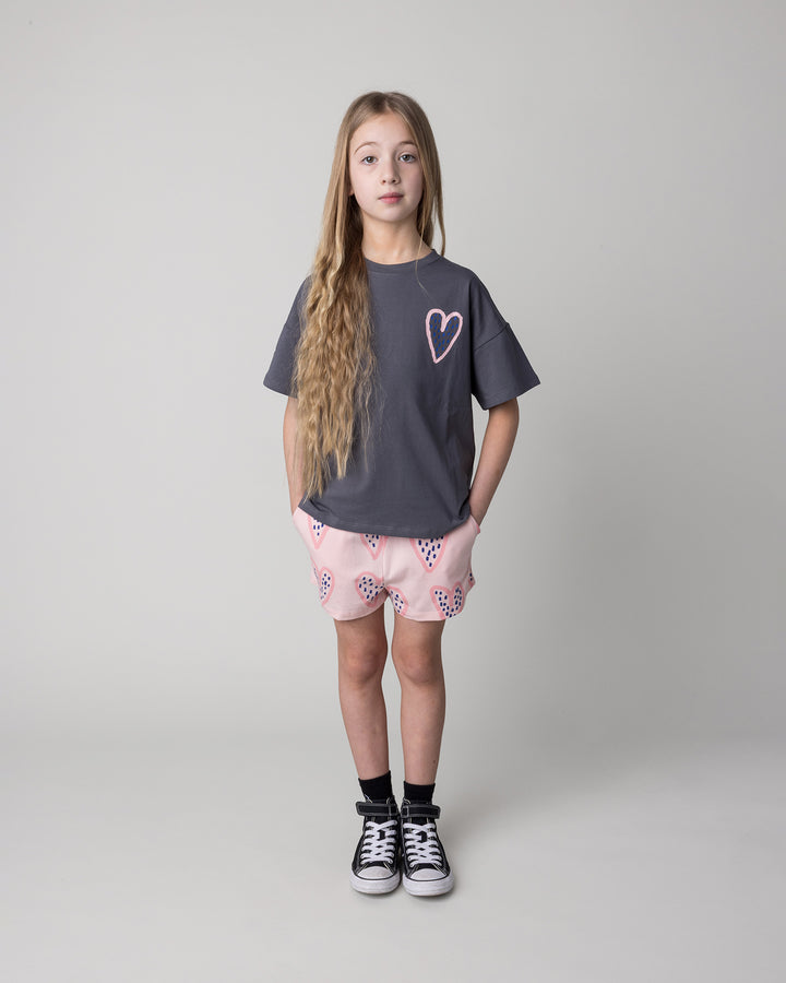 Kid wearing the Speckle Heart Tee in dark grey with the Speckle Heart Short in pink, front view