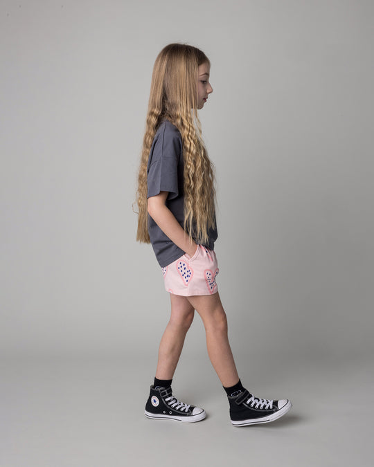 Kid wearing the Speckle Heart Tee in dark grey with the Speckle Heart Short in pink, side view