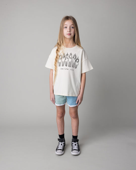 Kid wearing the Unicorn Club Tee in cream with the Sprint Short in mint and aqua and lilac, front view