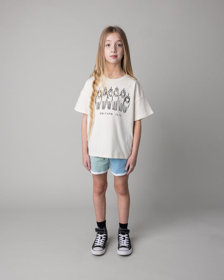Kid wearing the Unicorn Club Tee in cream with the Sprint Short in mint and aqua and lilac, front view