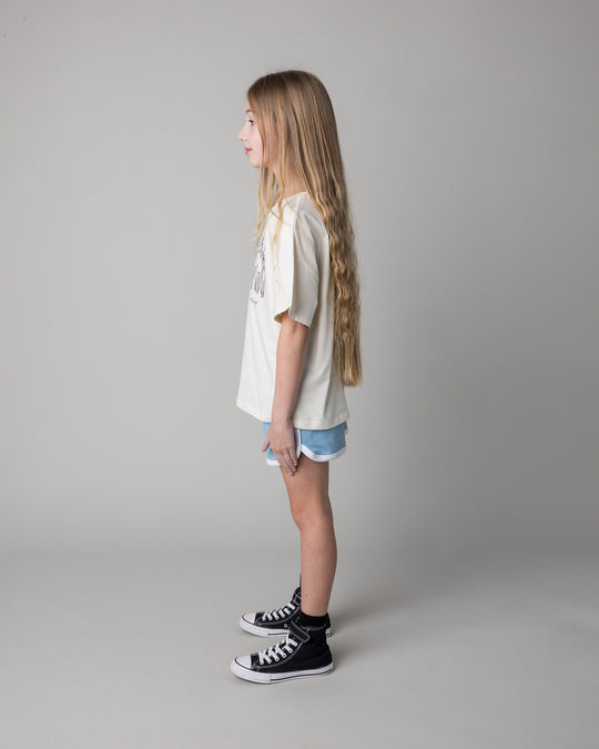 Kid wearing the Unicorn Club Tee in cream with the Sprint Short in mint and aqua and lilac, side view