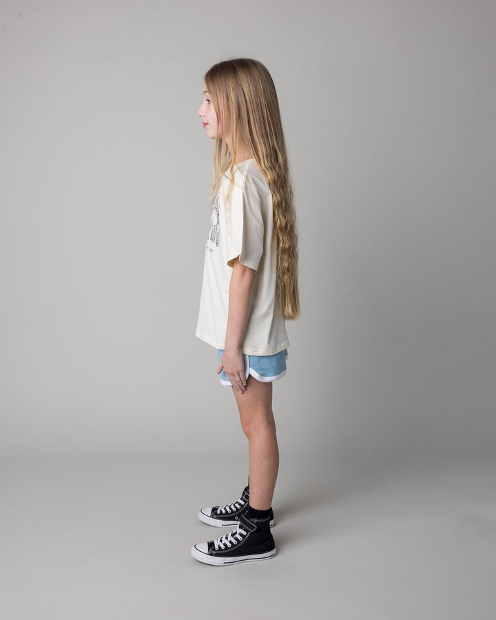 Kid wearing the Unicorn Club Tee in cream with the Sprint Short in mint and aqua and lilac, side view
