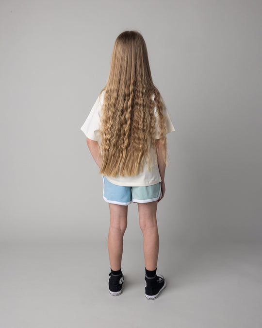 Kid wearing the Unicorn Club Tee in cream with the Sprint Short in mint and aqua and lilac, back view
