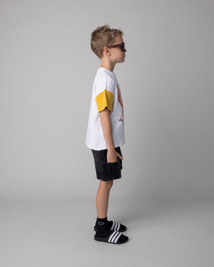 Kid wearing the Vacay Crayfish Tee in off white and mustard and orange, side view