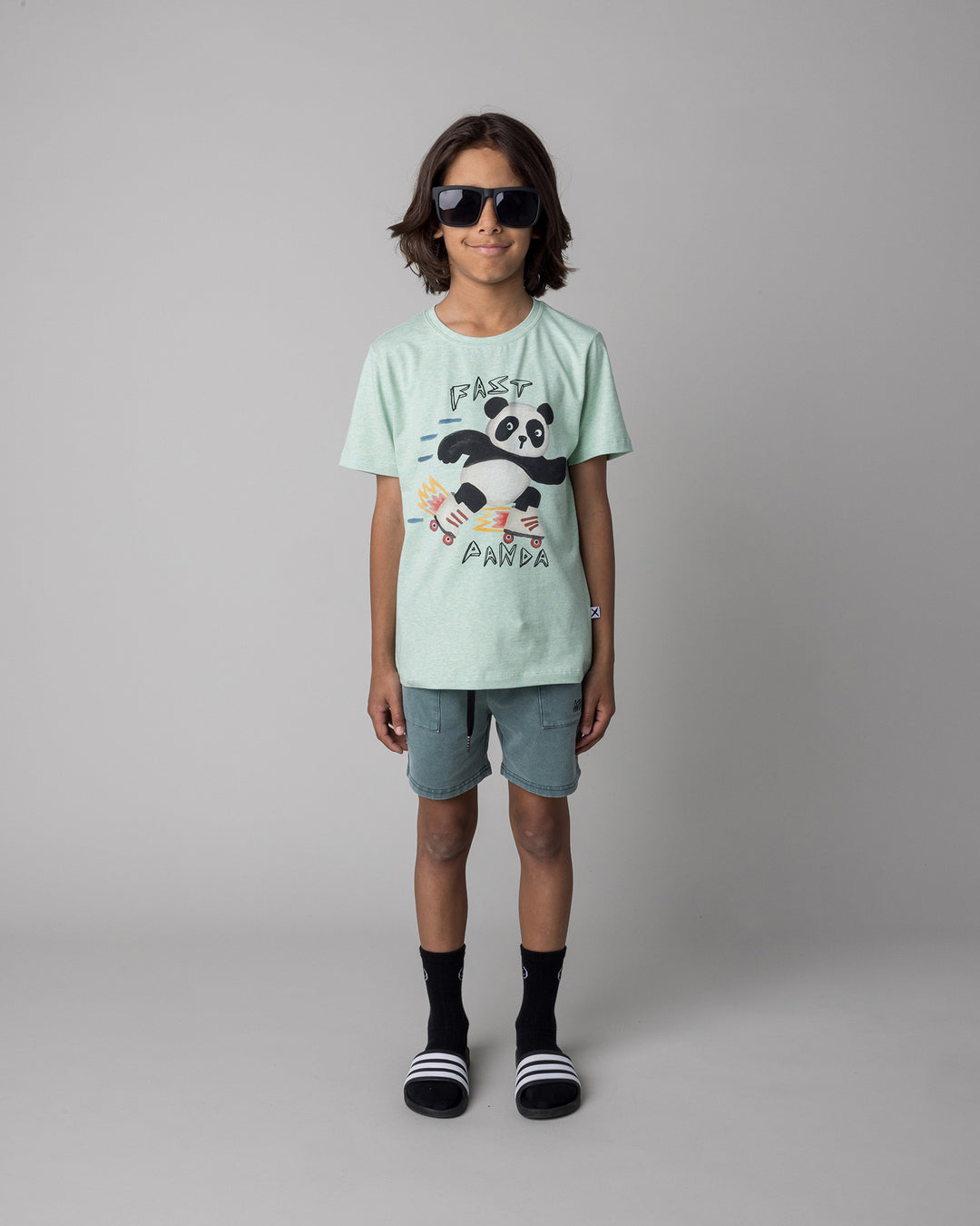 Kid wearing the Fast Panda Tee in green marle with the Blasted Track Short in forest wash, front view