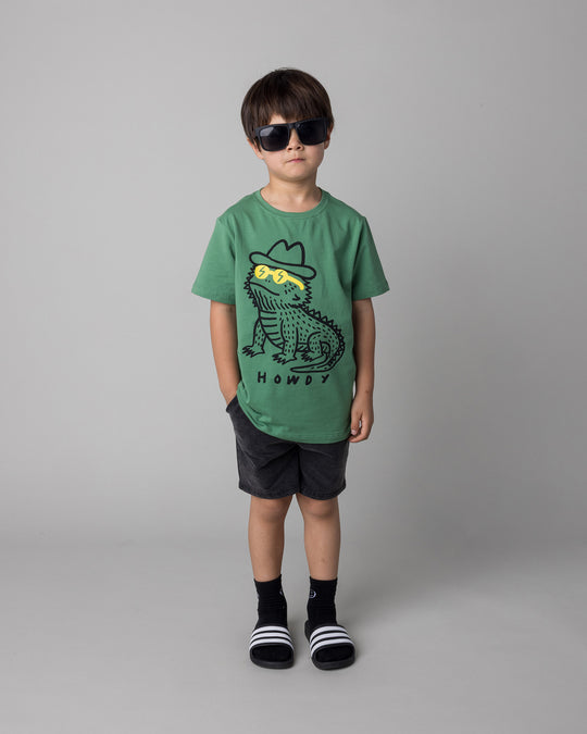 Kid wearing the Howdy Lizard Tee in turf with the Blasted Panel Short in black wash, front view
