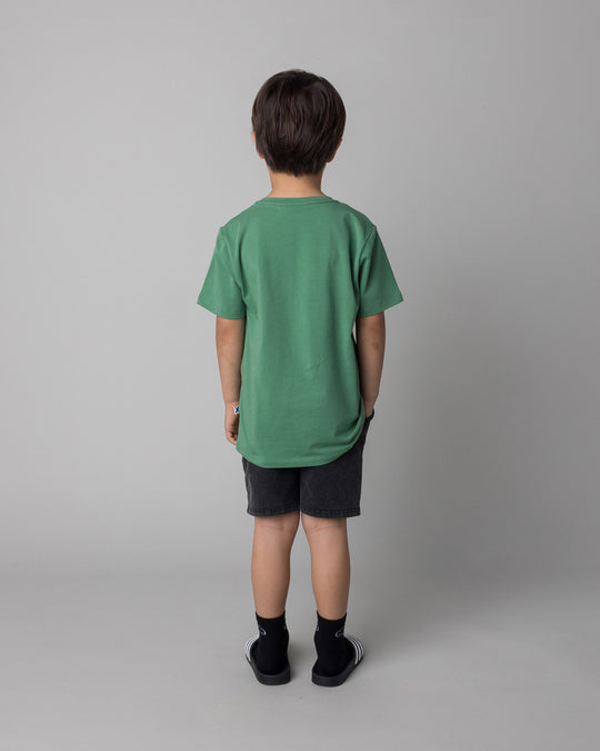 Kid wearing the Howdy Lizard Tee in turf with the Blasted Panel Short in black wash, back view