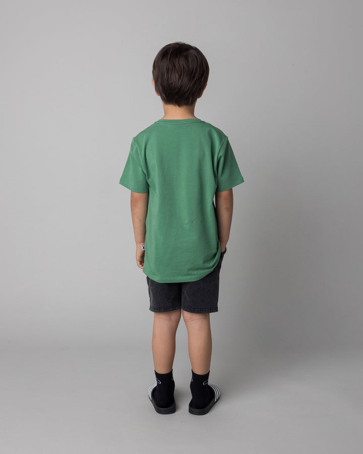 Kid wearing the Howdy Lizard Tee in turf with the Blasted Panel Short in black wash, back view