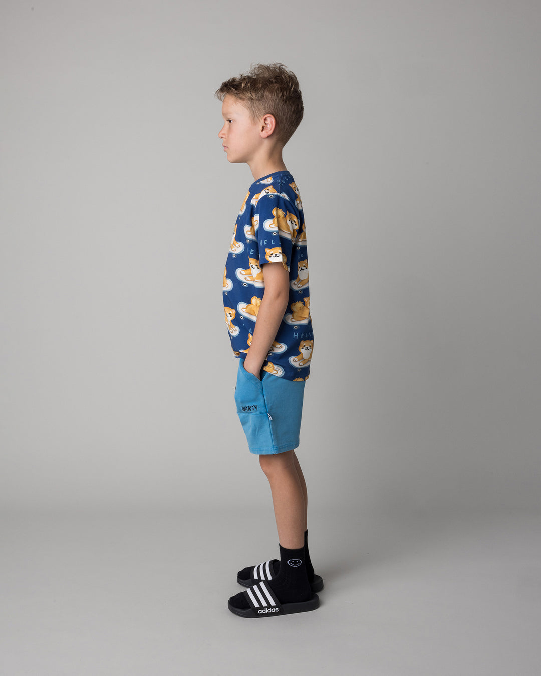 Kid wearing the Skate Puppy Tee in midnight with the Blasted Track Short in sky wash, side view