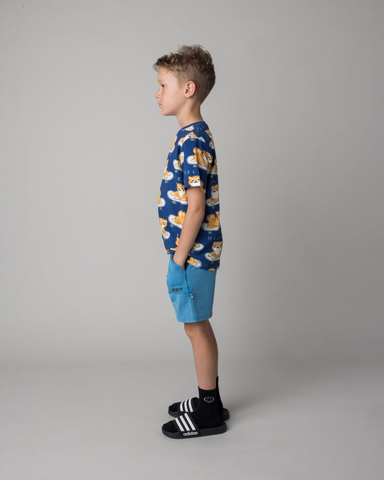 Kid wearing the Skate Puppy Tee in midnight with the Blasted Track Short in sky wash, side view
