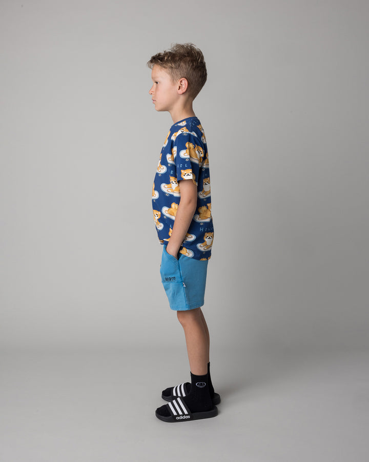 Kid wearing the Skate Puppy Tee in midnight with the Blasted Track Short in sky wash, side view