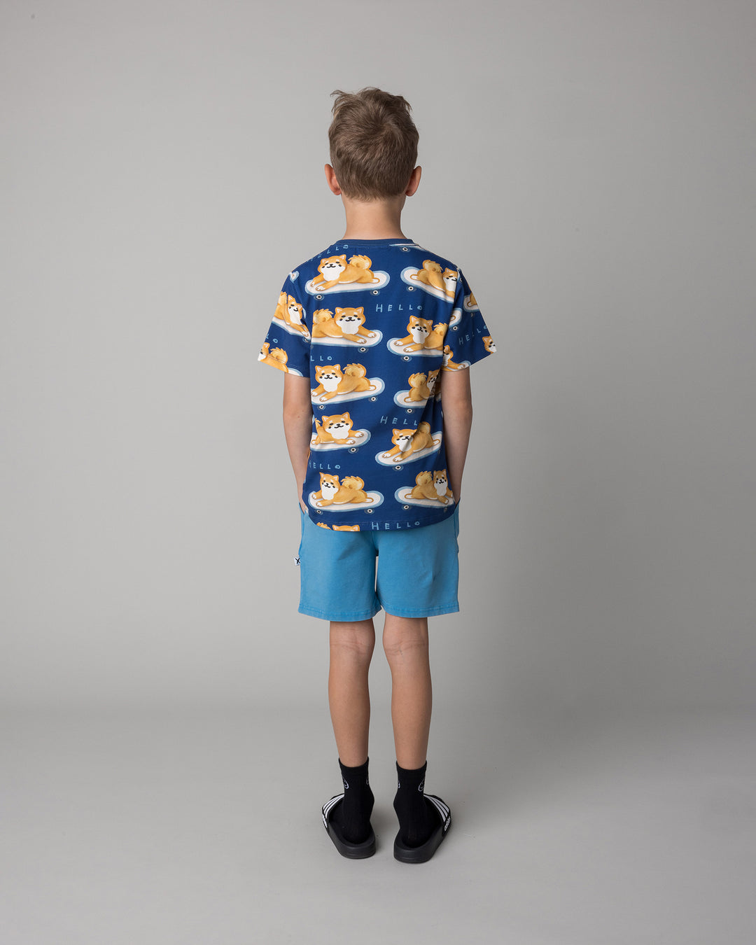 Kid wearing the Skate Puppy Tee in midnight with the Blasted Track Short in sky wash, back view