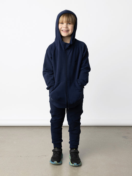 Minti kids clothing. Cosy zip through hoodie with kangaroo pockets for extra warmth! 2x2 rib trim on the hood, cuffs and hem. Small tonal Happy Face embroidery on the front. 330 Gram // Brushed Inside // 95% Cotton // 5% Elastane.