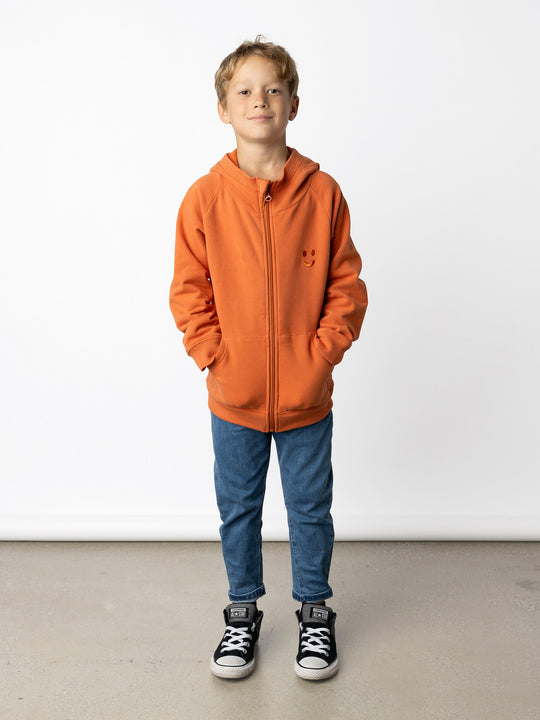 Minti kids clothing. Cosy zip through hoodie with kangaroo pockets for extra warmth! 2x2 rib trim on the hood, cuffs and hem. Small tonal Happy Face embroidery on the front. 330 Gram // Brushed Inside // 95% Cotton // 5% Elastane.
