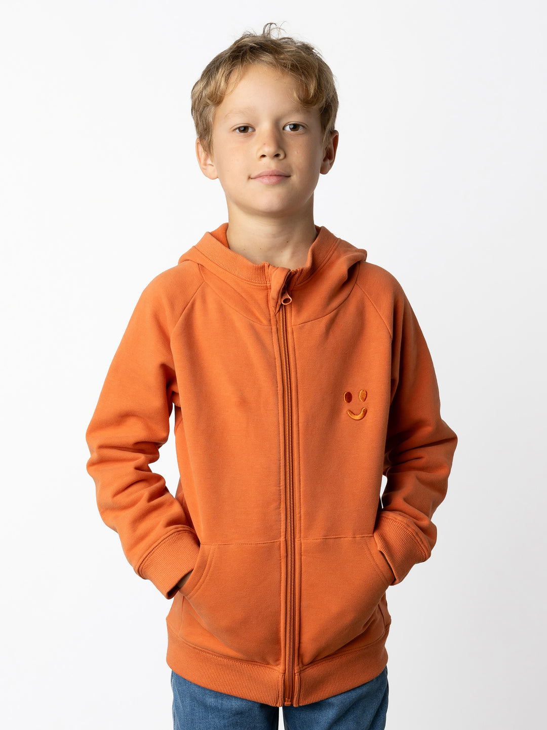 Minti kids clothing. Cosy zip through hoodie with kangaroo pockets for extra warmth! 2x2 rib trim on the hood, cuffs and hem. Small tonal Happy Face embroidery on the front. 330 Gram // Brushed Inside // 95% Cotton // 5% Elastane.