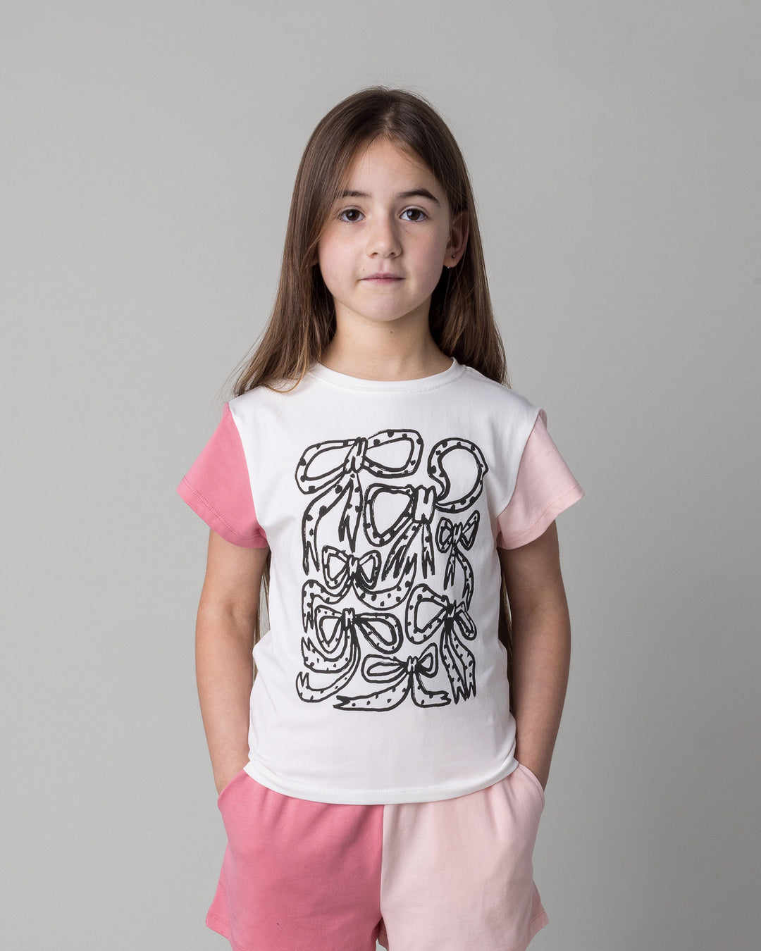 Close up of the Messy Bows Tee in white and pinks on a kid, front view