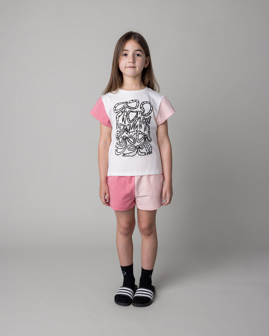 Kid wearing the Messy Bows Tee in white and pinks with the Two Tone Short in pinks, front view