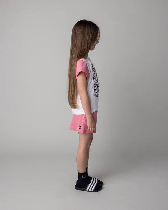 Kid wearing the Messy Bows Tee in white and pinks with the Two Tone Short in pinks, side view