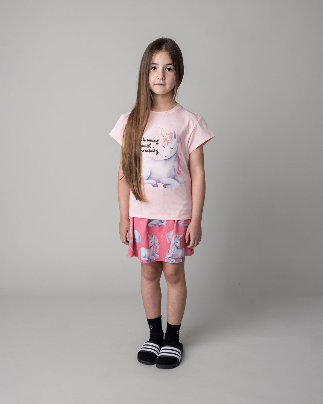 Kid wearing the Daydreaming Unicorn Skirt in candy with the Daydreaming Unicorn Tee in pink marle, front view