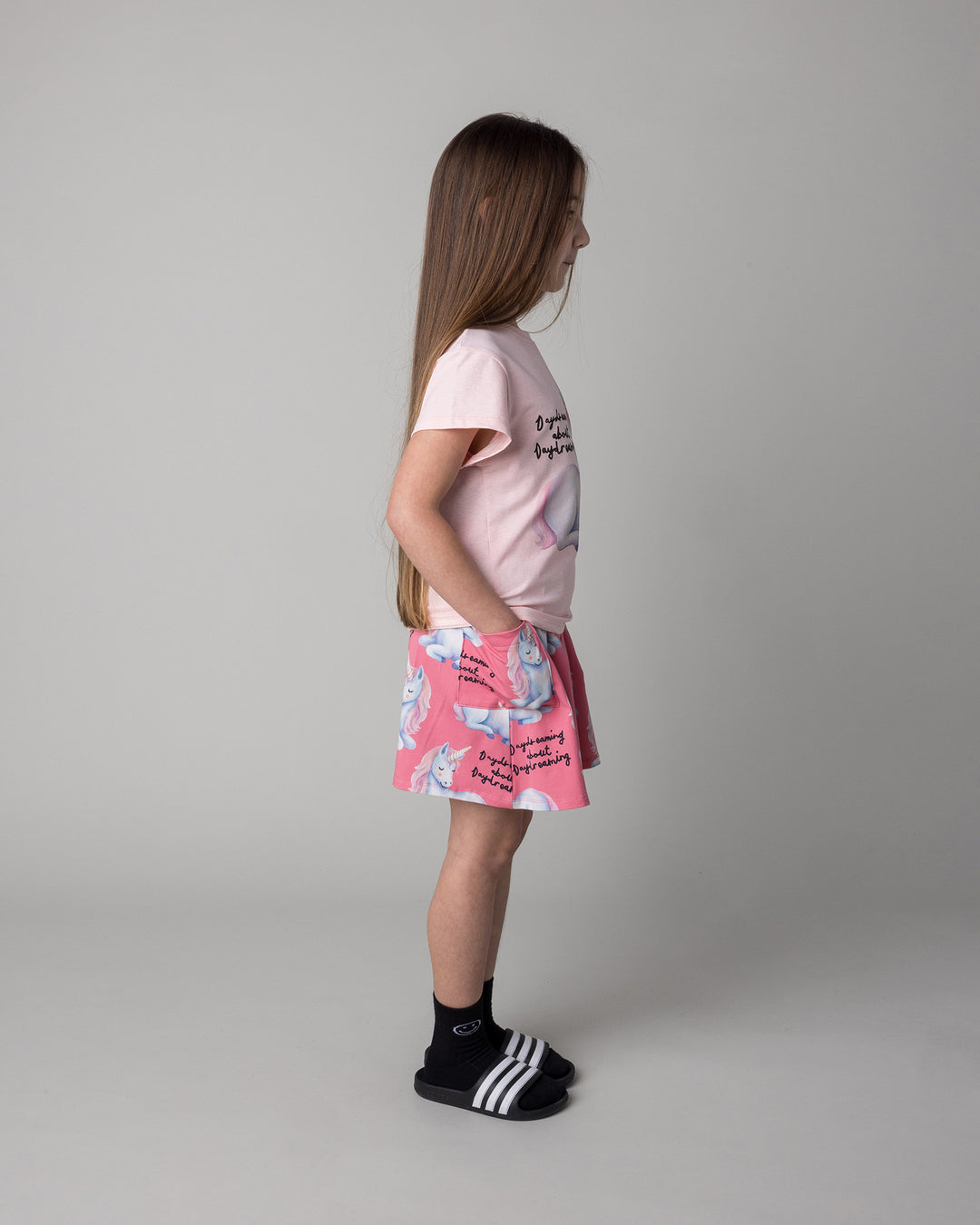 Kid wearing the Daydreaming Unicorn Skirt in candy with the Daydreaming Unicorn Tee in pink marle, side view
