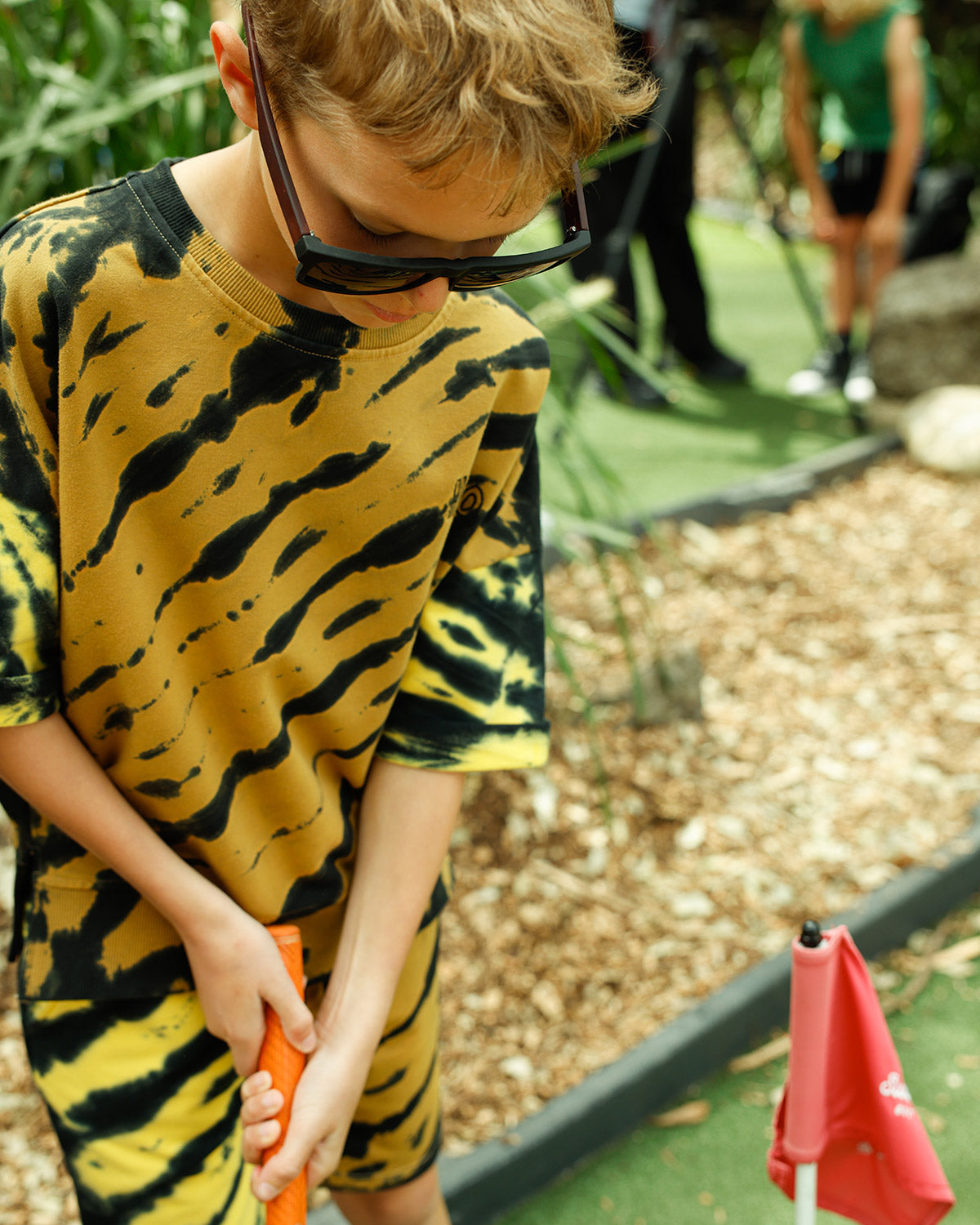 Kid in the Minti Duo Tie Dye crew and short at mini golf